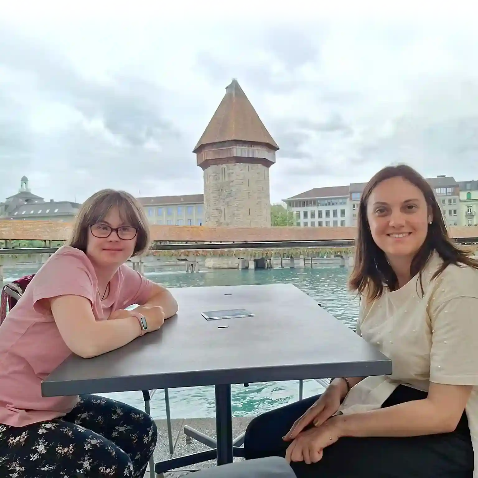 Zwei junge Frauen sitzen in Gartenrestaurant. Im Hintergrund die Kapellbrücke Zwei junge Frauen sitzen in Gartenrestaurant. Im Hintergrund die Kapellbrücke